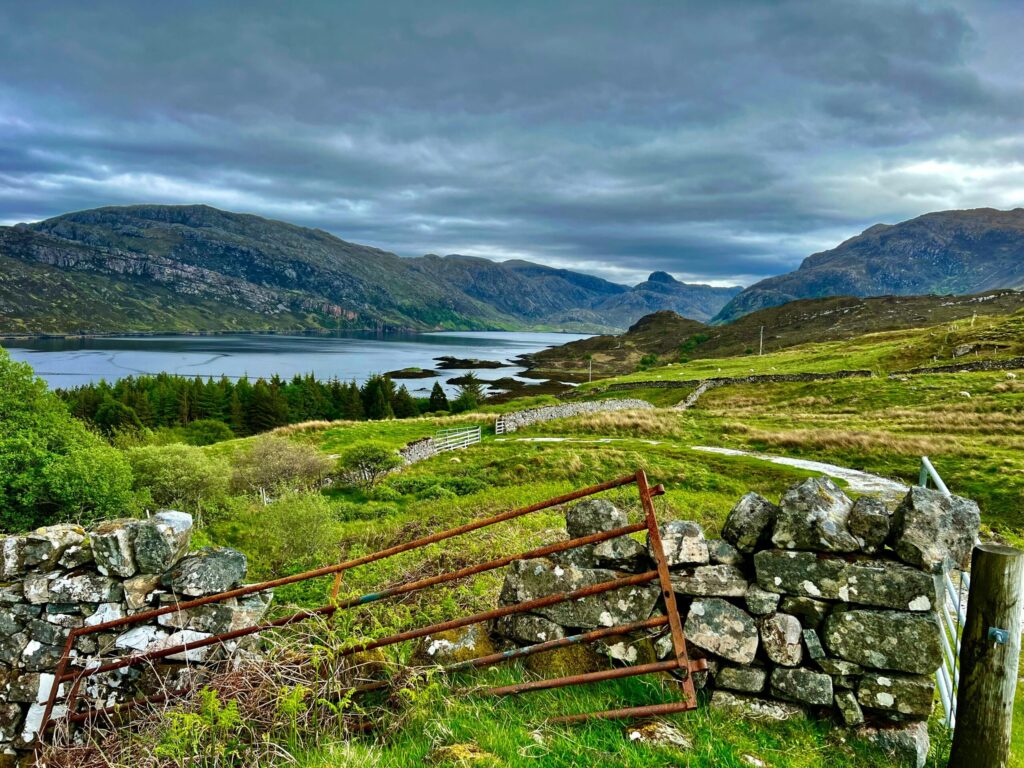 Breathtaking view of rolling hills and a serene lake framed by a rustic stone fence.